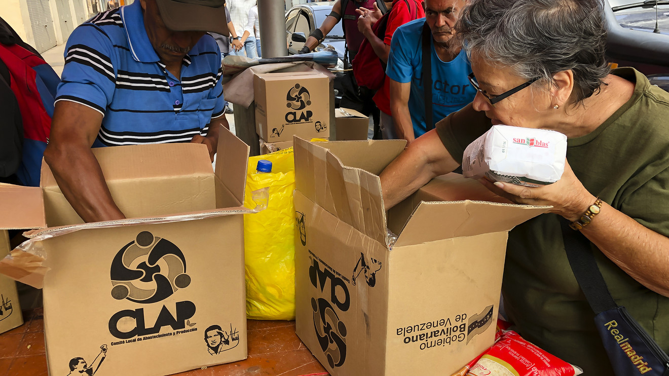 Vizinhos em Caracas, Venezuela, abrem a cesta básica CLAP. O programa de abastecimento de comida é a principal fonte de alimento para estimados 15% de Venezuelanos. 