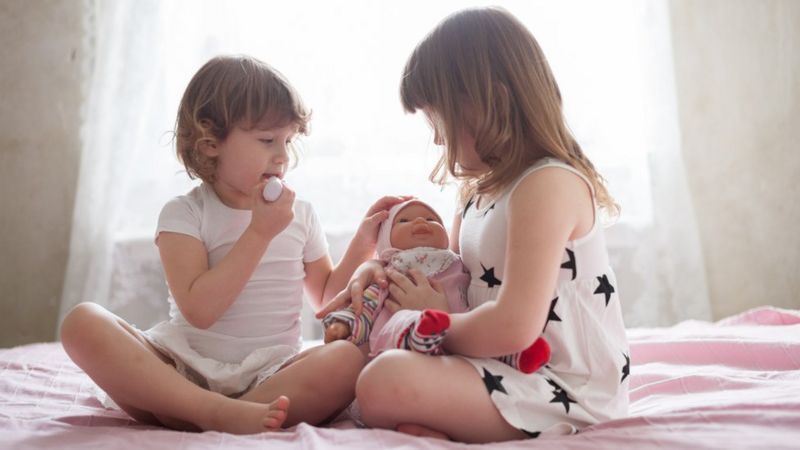 Foto mostra meninas brincando de boneca